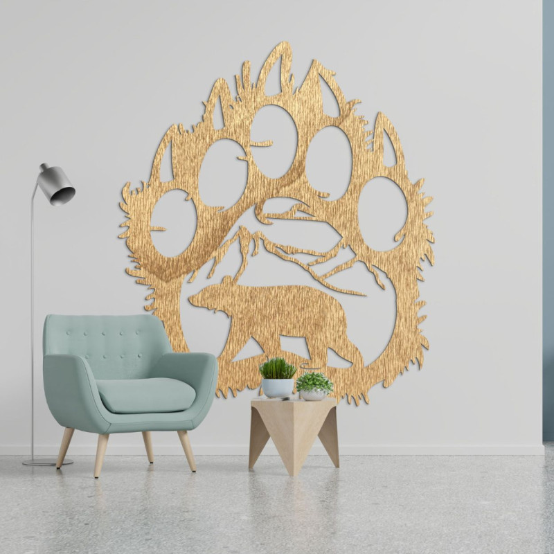 Egy medvelábnyom fából készült képe, amelynek belsejében egy hegyek alatt sétáló medve sziluettje van faragva.